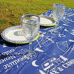 two wine glasses sitting on top of a blue and white cloth covered picnic tablecloth