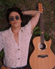 a man laying on the ground next to a guitar and looking up at the sky