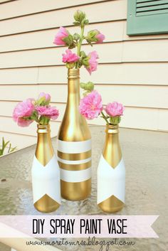 three gold vases with pink flowers in them on a patio table next to a house