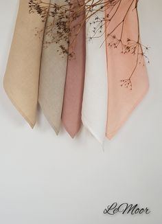 four different colors of napkins with dried flowers on the top and one in front