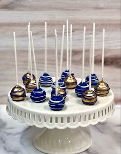 there are many blue and gold candys on the cake plate with toothpicks