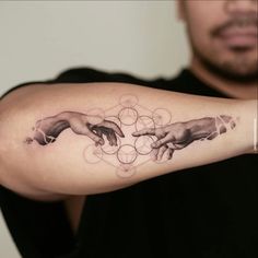 a man with a tattoo on his arm that has the creation of hands touching each other