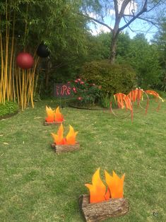 an outdoor fire pit in the middle of a grassy area with wooden logs and orange flames