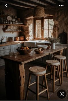 a wooden table sitting in the middle of a kitchen next to two stools and a sink