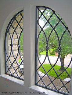 two arched windows are shown in the middle of a room with green grass and trees