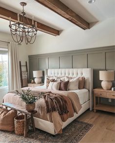 a large bed sitting in a bedroom under a chandelier next to a window