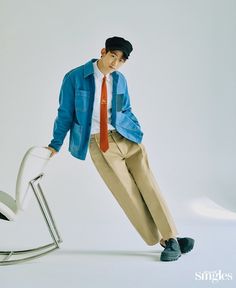 a young man leaning on a chair with his legs crossed and wearing a blue jacket