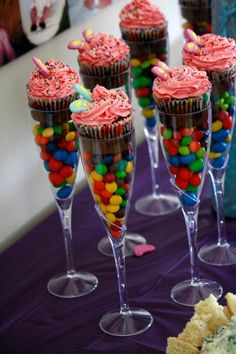 cupcakes and candy in wine glasses on a purple tablecloth with confetti