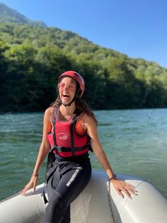 a woman sitting on top of a boat in the water with her arms out and smiling