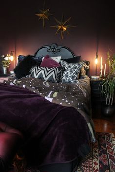 a bed that has some pillows on top of it with candles in the corner next to it