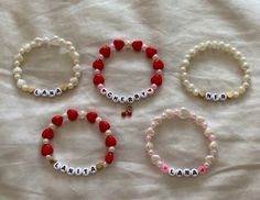 three bracelets with name charms on them sitting on a white sheet covered in fabric