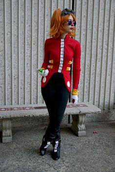 a woman dressed up as a clown standing next to a bench