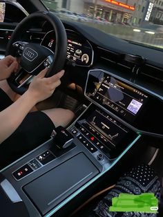 a woman driving an audi car in the city with her hands on the steering wheel