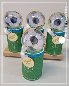 four soccer balls are sitting on top of each other in green cups with gold rims