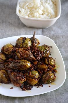 cooked brussel sprouts on a white plate with rice in the background