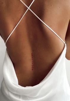 the back of a woman's white dress with red writing on her lower back