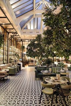 the interior of a restaurant with tables, chairs and plants on the floor in front of glass walls