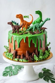 a cake decorated with green icing and dinosaur figurines sitting on top of it