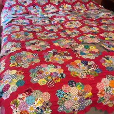 a bed with a red bedspread covered in lots of different colored patchwork