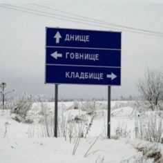 a blue street sign sitting on the side of a snow covered road