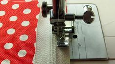 the sewing machine is working on the red and white polka dot fabric