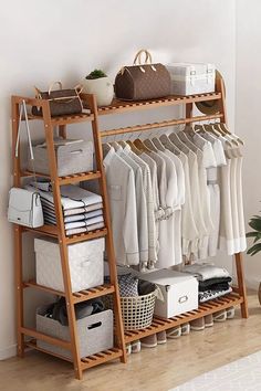 a wooden rack with clothes and bags on it next to a plant in a room