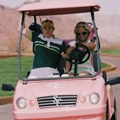 two people in a pink golf cart with the driver smiling and waving to the camera