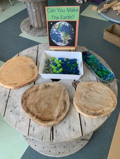 a table with three wooden plates and a sign that says can you make the earth?