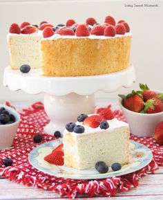 a white cake with berries on top is sitting on a red and white tablecloth