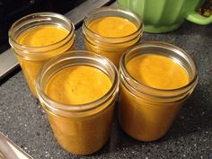 four jars filled with yellow liquid sitting on top of a counter next to an oven