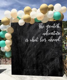 a chalkboard with balloons on it that says the greatest adventure is what lies ahead