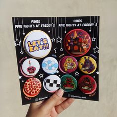 a hand holding a pack of buttons with the words let's eat on them