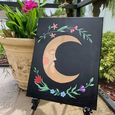 a painting on an easel next to a potted plant with flowers in it