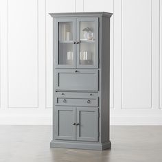 a tall gray cabinet with glass doors and drawers on the bottom, in front of a white wall