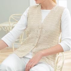 a woman sitting in a chair wearing a crocheted vest and white pants with her hands on her hips