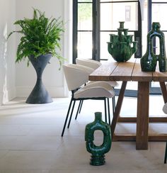 a dining room table with chairs and vases on it