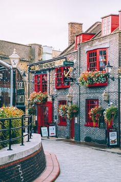 a cobblestone street lined with brick buildings and red shutters on the windows