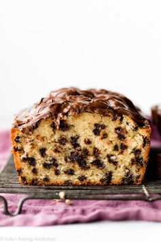 a loaf of chocolate chip banana bread on a cooling rack with one slice cut off