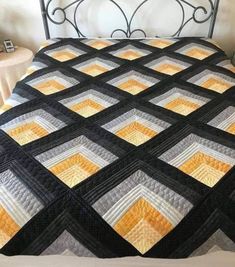 a bed with a black and yellow quilt on it