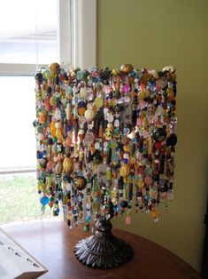 a table with a lamp made out of many different items on it and a window in the background