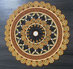 an intricately designed doily is shown on a wooden surface with black and gold accents