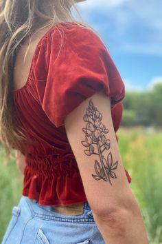 a woman with a flower tattoo on her left arm and right arm behind her back