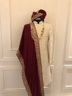 a dress on display in front of a white door with a red and gold shawl