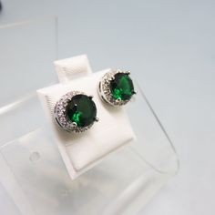 These classic emerald and clear cubic zirconia earrings are gorgeous.  They measure 3/8th inches in diameter. The metal is rhodium plated and they are in MINT condition.  Think ahead to the holidays. These would be smashing with a simple suit or dress.   We will send these to you in a lovely gift box for stellar gift presentation. If you like old sterling silver jewelry, bolo ties, vintage costume jewelry and accessories, kindly check out my store for more delights!   www.etsy.com/shop/PANDPF Classic Green Diamond Earrings, Green Cubic Zirconia Fine Jewelry Earrings, Green Cubic Zirconia Earrings With Prong Setting, Emerald Earrings With Diamond Accents, Green Cubic Zirconia Earrings Fine Jewelry, Green Round Earrings With Halo Setting, Green Diamond Round Cut Earrings, Classic Green Halo Earrings, Green Diamond Accented Round Earrings