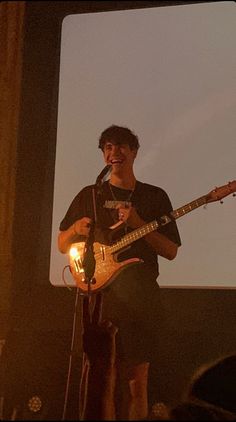 a man playing guitar while singing into a microphone