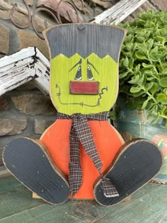 a wooden cutout of a scarecrow sitting next to a potted plant