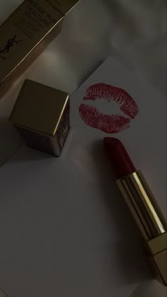 the lipstick is laying on top of paper next to it's box and pen