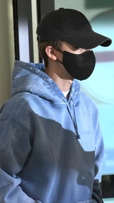 a man wearing a black hat and blue sweatshirt with a face mask on his face