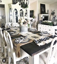 a dining room table is set with place settings and black and white plates on it