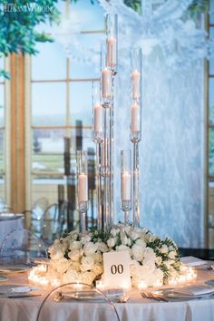 a centerpiece with candles and flowers is displayed in front of a window at the reception